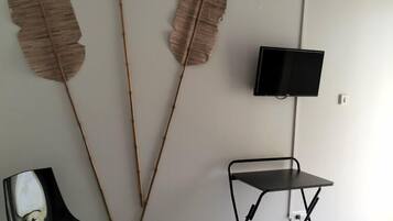 Ein Schlafzimmer mit einem Bett, einem Sessel, einem kleinen Tisch und drei großen Wanddekorationen im Blattstil.