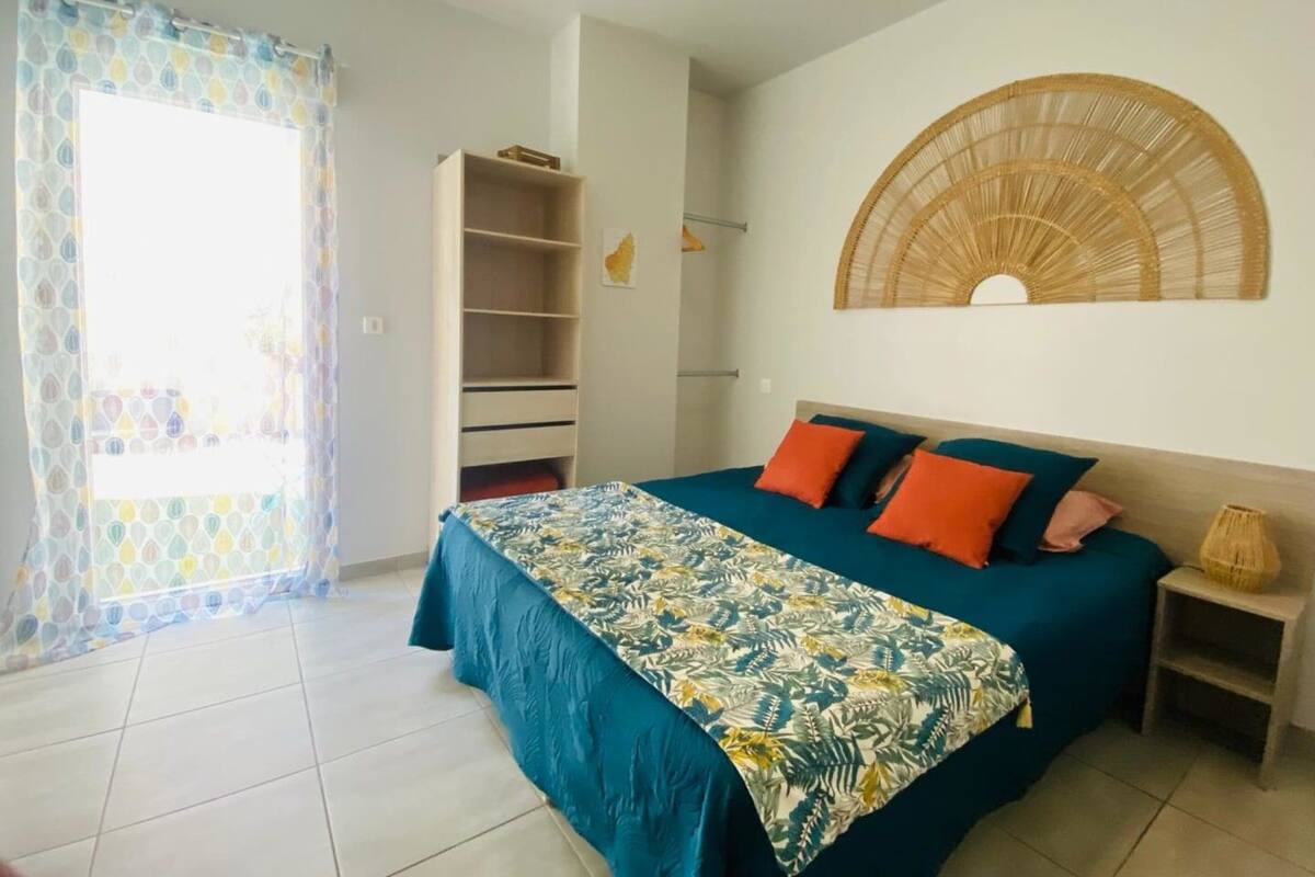 A bedroom with a bed, a wardrobe, a small table, and a decorative wall piece.