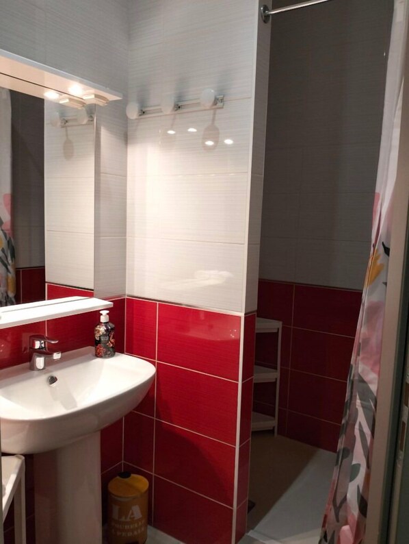 Ein Badezimmer mit einem weißen Waschbecken, roten Fliesen und einem Spiegel.
