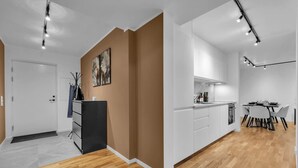 Een moderne keuken met witte kasten, een zwart aanrecht en een eethoek met een tafel en stoelen.