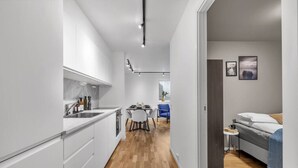 Een moderne keuken met witte kasten, een houten vloer en een eethoek met een blauwe stoel.