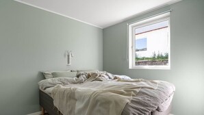 Ein Schlafzimmer mit einem Bett, einem Fenster und einer Wandleuchte.