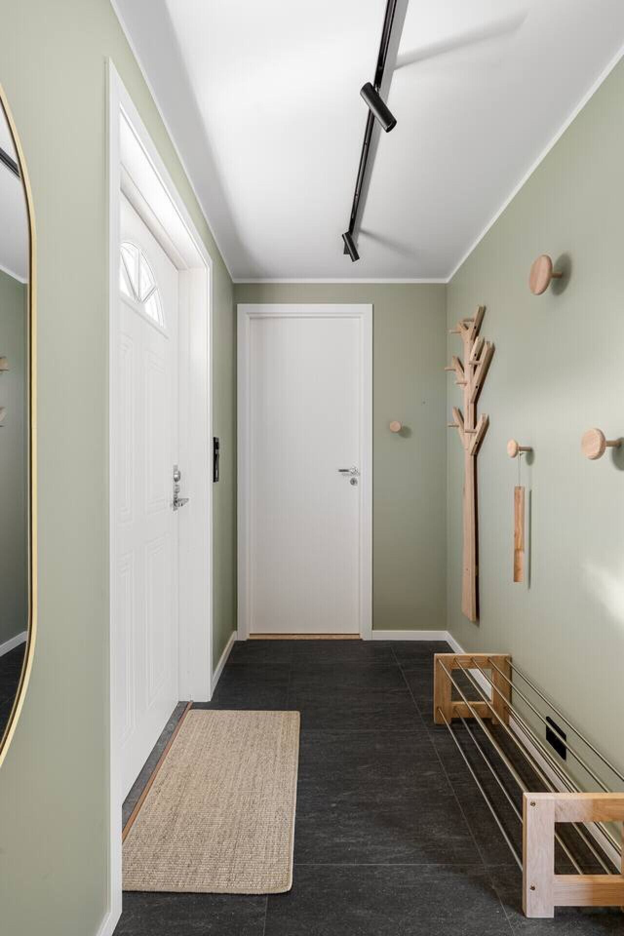 Ein Flur mit einer weißen Tür, einem kleinen Teppich und Holzdekorationen an der Wand.