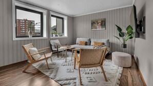 Een moderne woonkamer met een bank, stoelen, een salontafel en een groot raam met uitzicht op de stad.