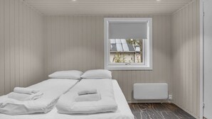 Ein schlicht eingerichtetes Schlafzimmer mit Bett, Fenster und Heizkörper.