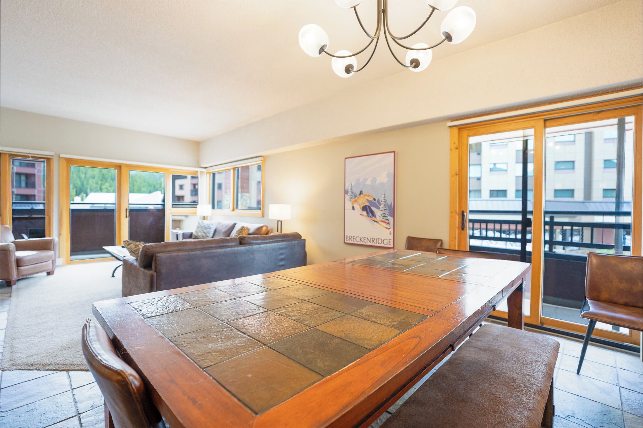Amplia sala de estar con una gran mesa de madera, un sofá y un balcón con vistas.