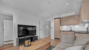 Un salon moderne avec un téléviseur à écran plat, une table basse en bois et un canapé.