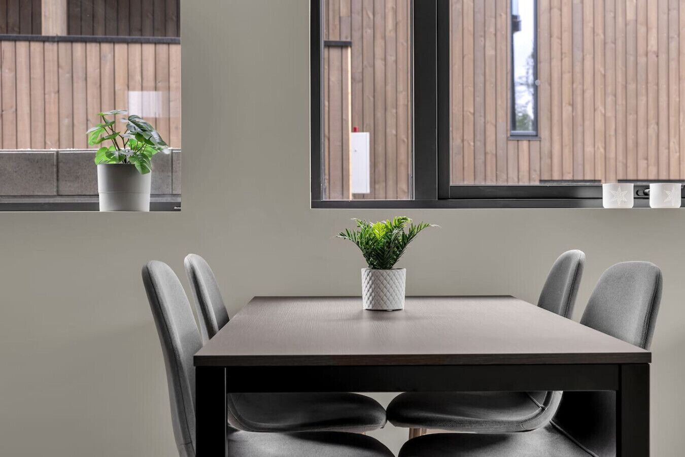 A modern dining area with a table, chairs, and potted plants.
