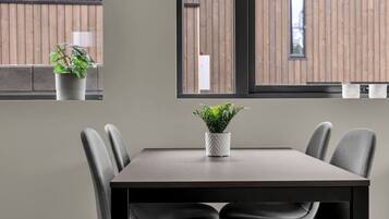 A modern dining area with a table, chairs, and potted plants.