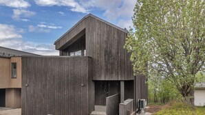 Un bâtiment moderne avec une façade en bois, un escalier menant à un étage supérieur et un arbre en arrière-plan.