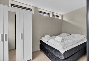 Une chambre à coucher avec un lit, une armoire et des fenêtres de toit.