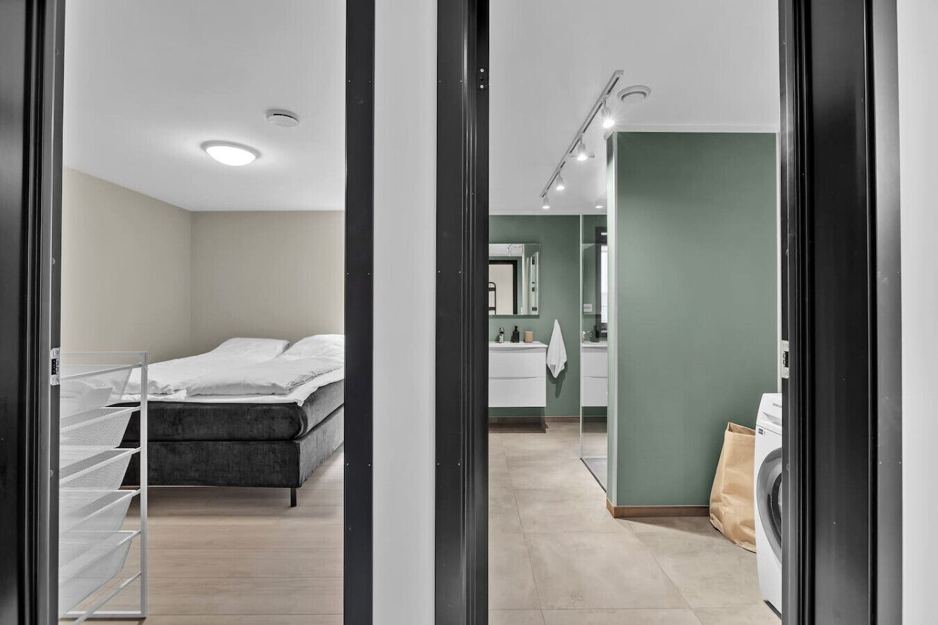 A modern bedroom with a bed, a walk-in closet, and a bathroom with a sink and mirror.
