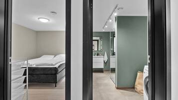 A modern bedroom with a bed, a walk-in closet, and a bathroom with a sink and mirror.