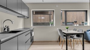 Une cuisine moderne dotée d’un four encastré, d’un évier en acier inoxydable et d’un coin repas avec une table et des chaises.
