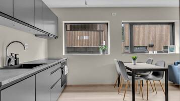 A modern kitchen with a built-in oven, a stainless steel sink, and a dining area with a table and chairs.