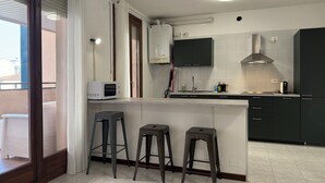 A modern kitchen with a microwave, sink, and bar stools.