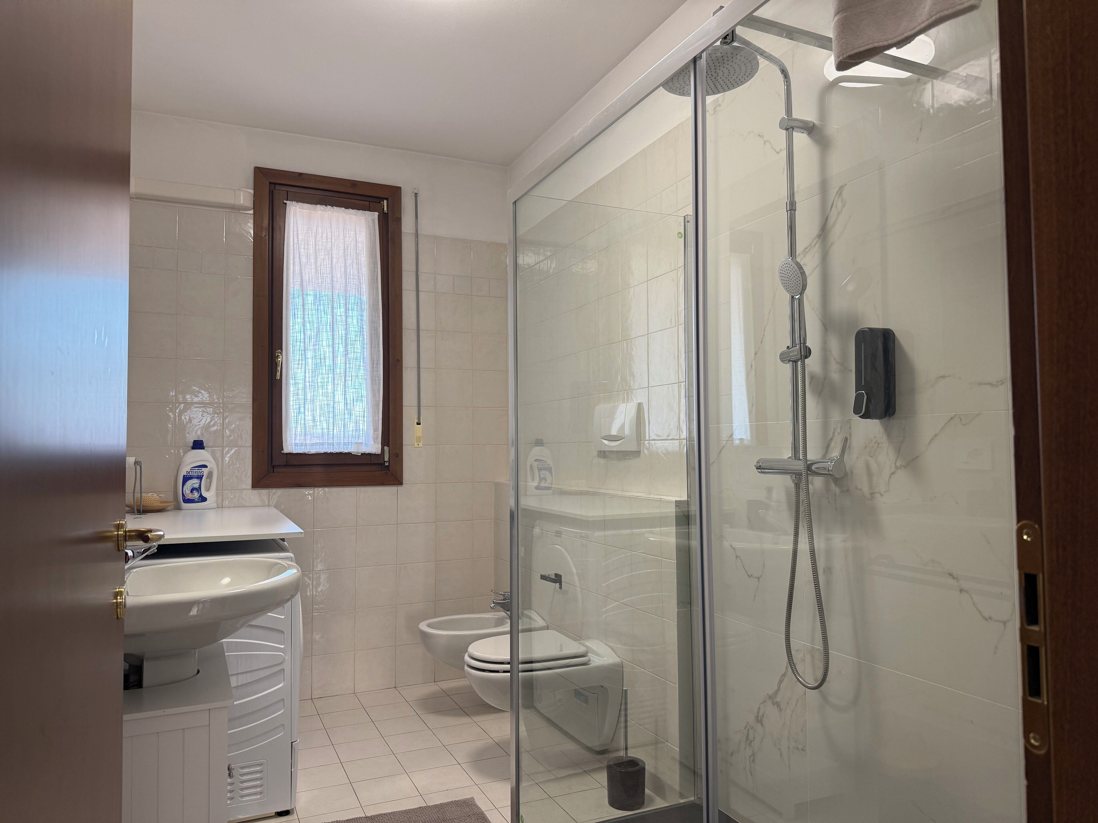 A modern bathroom with a glass-enclosed shower, a toilet, and a sink.