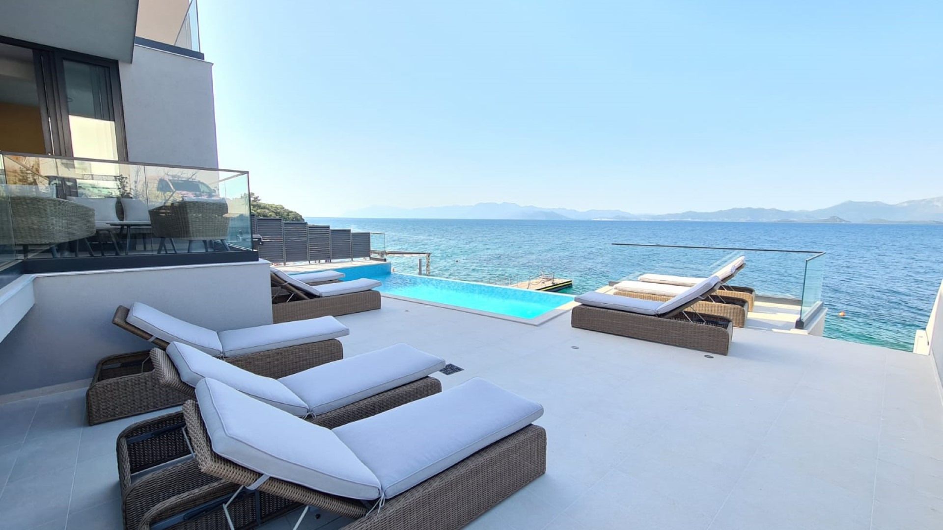 Une terrasse sur le toit avec une piscine, des chaises longues et une vue sur la mer.