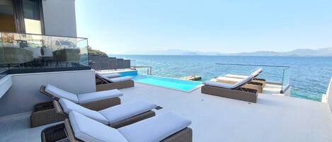 Une terrasse sur le toit avec une piscine, des chaises longues et une vue sur la mer.