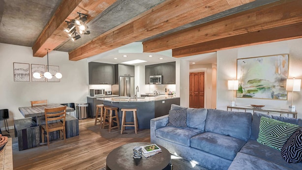 Una cocina moderna con una isla central, mesa de comedor de madera y taburetes de bar.
