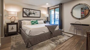 Un dormitorio con una cama grande, dos mesitas de noche, un espejo y una ventana con cortinas.