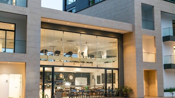 Un hotel moderno con zona de piscina, un restaurante en la planta baja y una planta superior con mobiliario.
