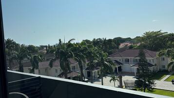 A balcony with a table and chairs, overlooking a residential area with houses and palm trees.
