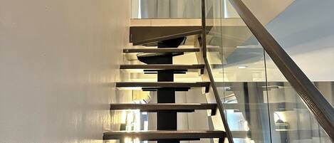Una escalera moderna con barandas de vidrio y peldaños de madera.