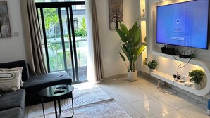 Una sala de estar moderna con un televisor de pantalla plana, un sofá, una mesa de centro y una planta en maceta.
