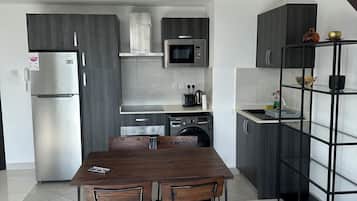 A modern kitchen with dark wood cabinets, stainless steel appliances, and a dining area with a wooden table and chairs.