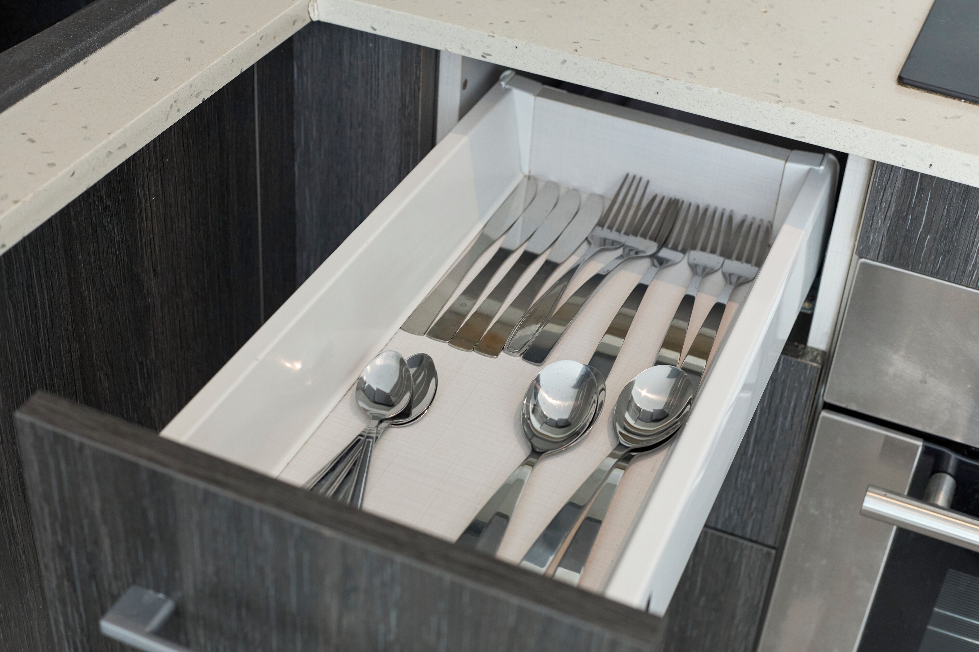 A drawer with neatly arranged utensils including spoons, forks, and knives.