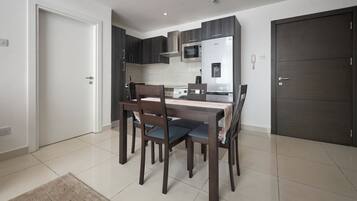 A modern kitchen with dark cabinetry, a built-in microwave, and a dining area with a table and chairs.