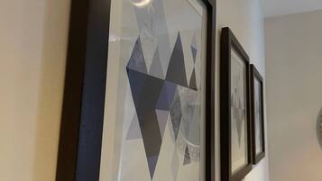 A wall with framed geometric artwork and a vase of red flowers.