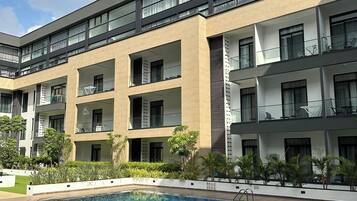 A modern multi-story hotel with a swimming pool, outdoor seating, and balconies.