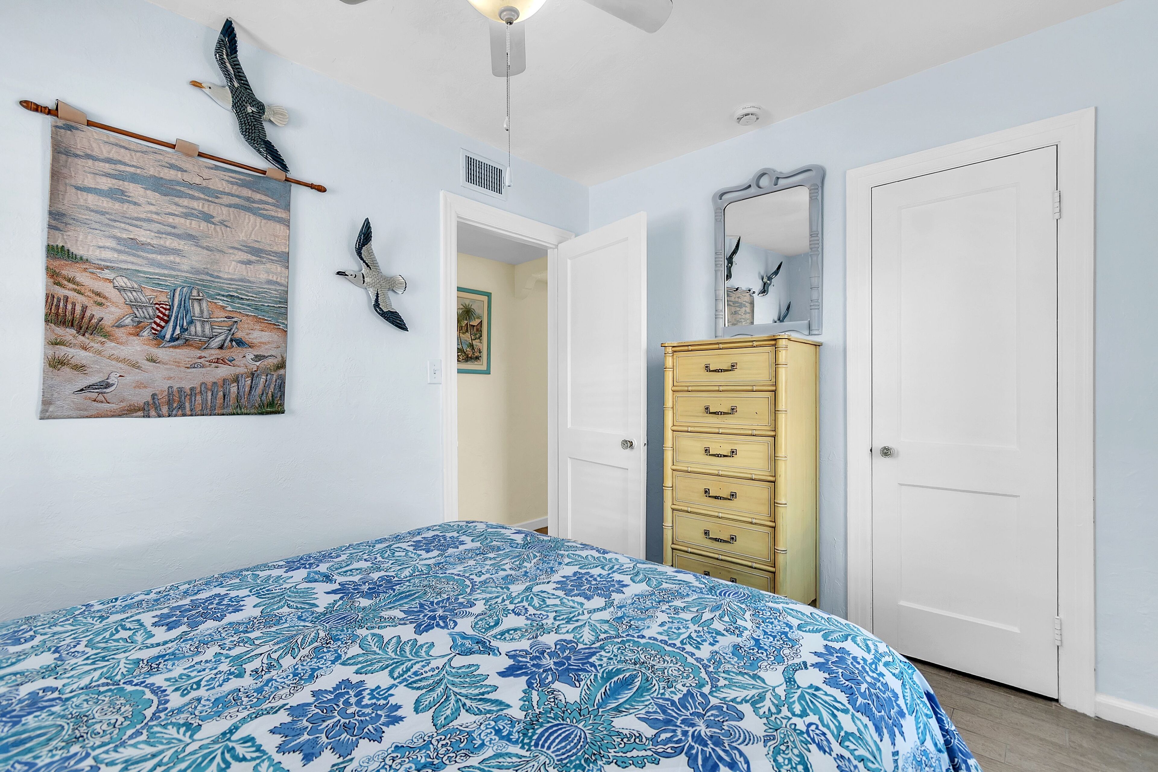 A bedroom with a bed, a dresser, a door, and wall art.
