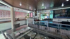 Un restaurant doté d’une salle à manger avec des parois en verre, de meubles en osier et un plafond en bois.