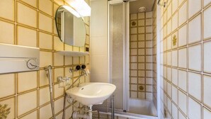 A bathroom with a white sink, a mirror, and a shower enclosure. - Hotel Sterne - Apartment with Balcony (Beatenberg)