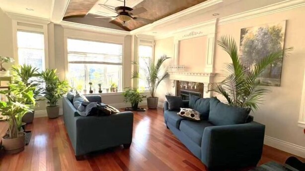 A spacious living room with a large sofa, a fireplace, and several potted plants. - Vancouver Garden Hotel (Richmond)