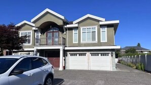 A two-story house with a garage, a balcony, and a driveway. - Vancouver Garden Hotel (Richmond)