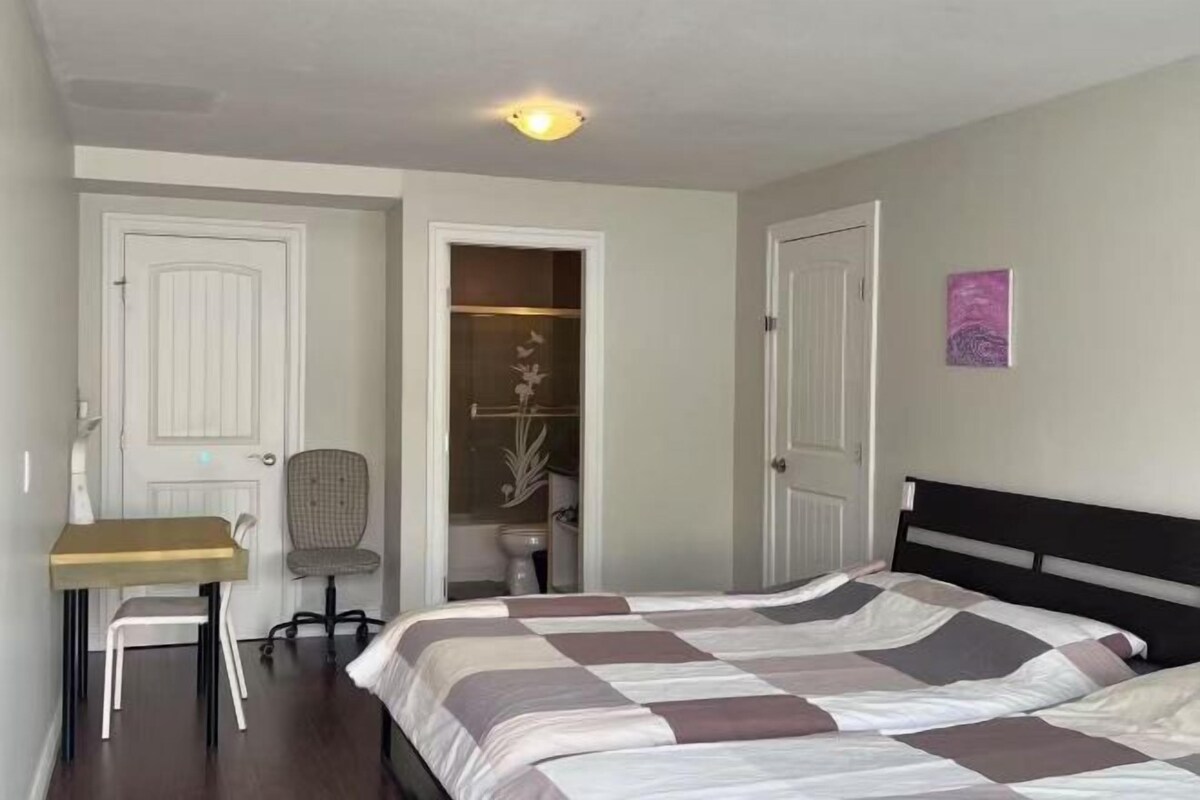 A bedroom with a bed, a desk, and a chair. There are two doors, one leading to a closet and another to a bathroom.