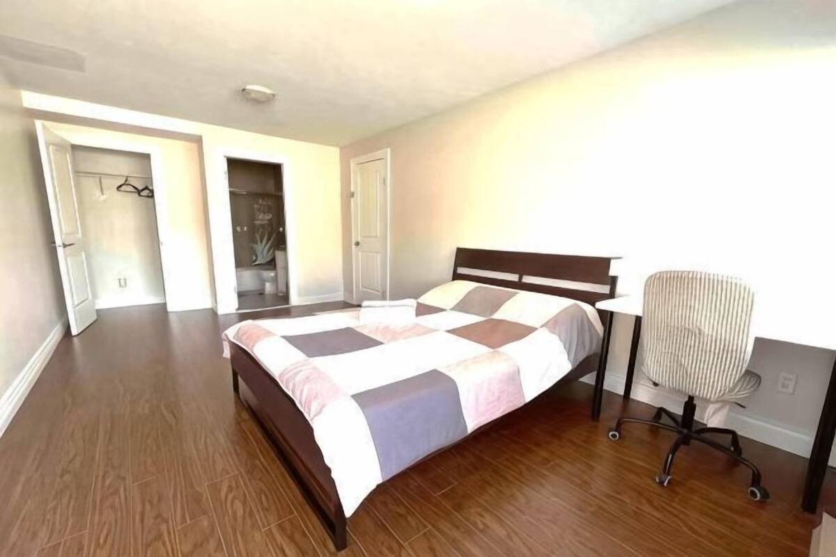 Ein Schlafzimmer mit einem Bett, einem Schreibtisch und einem Stuhl. Mehrere Türen führen in andere Räume.