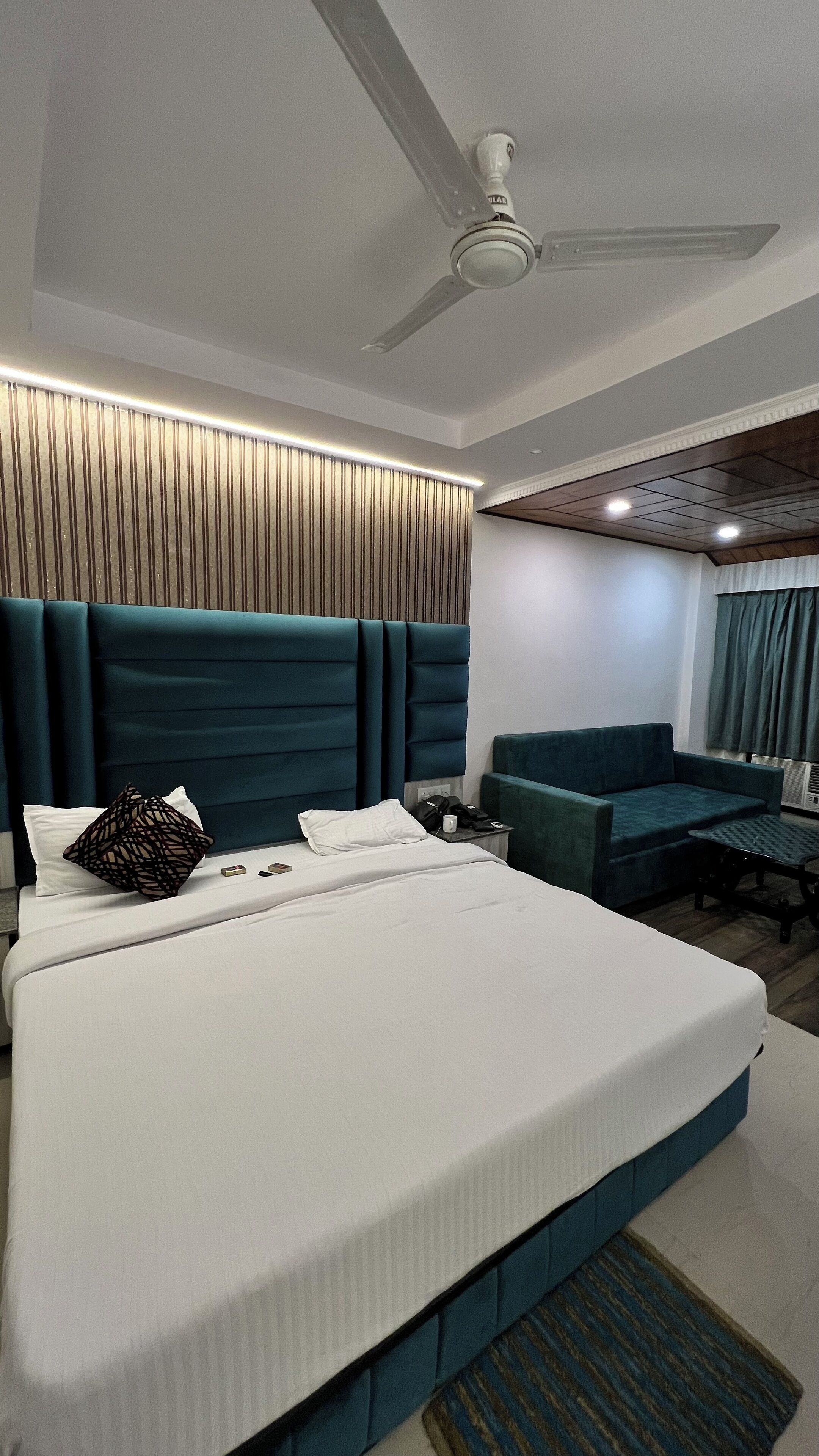 Ein modernes Hotelzimmer mit einem großen Bett, einer Couch und einem Deckenventilator.