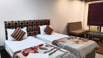 A hotel room with two single beds, a small table, a chair, and a large window.
