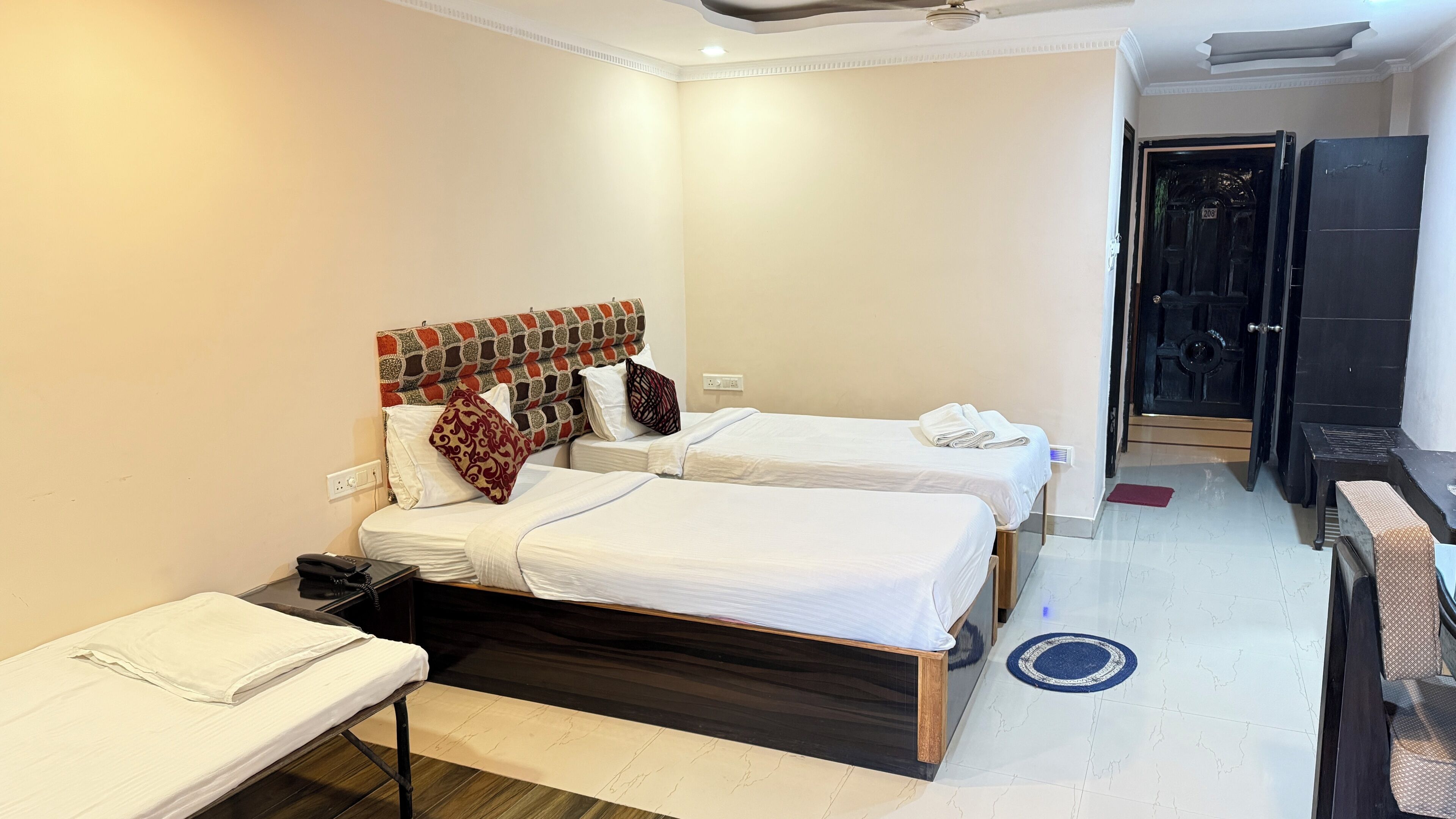 Quarto de hotel com duas camas, uma escrivaninha e um guarda-roupa.