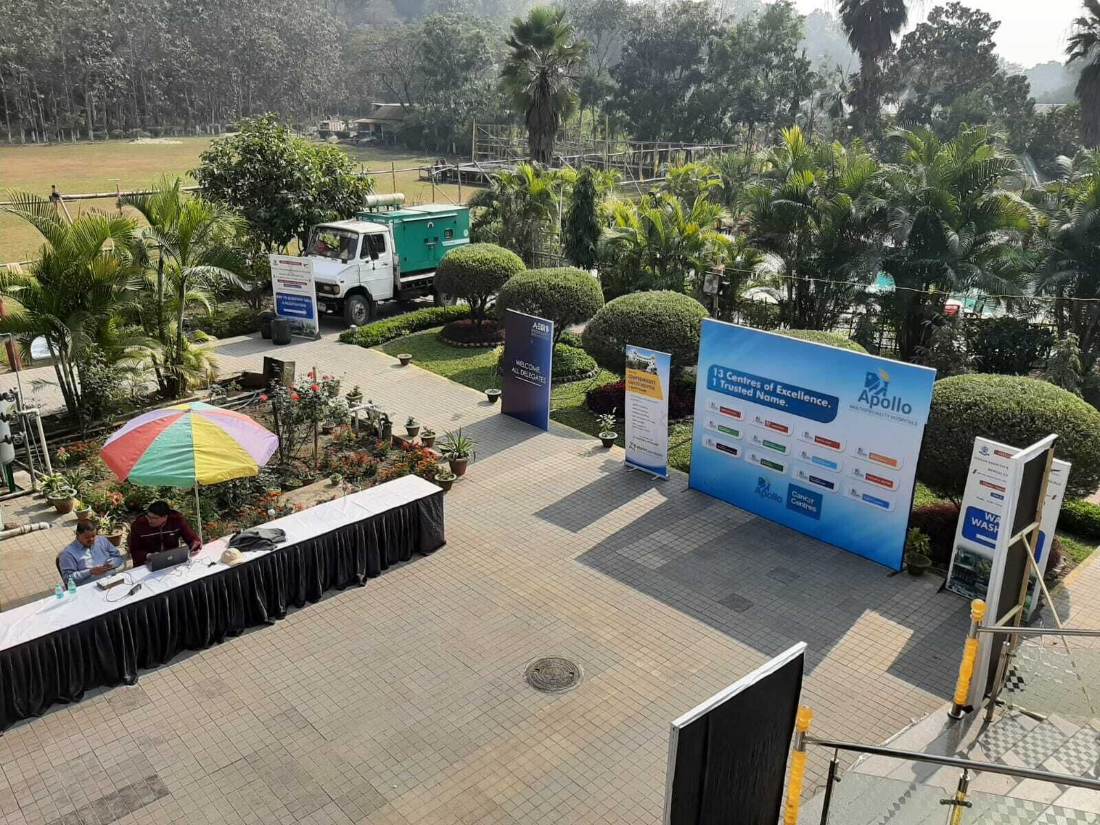 An outdoor area with a stage, seating, and a large sign for Apollo Hospitals.