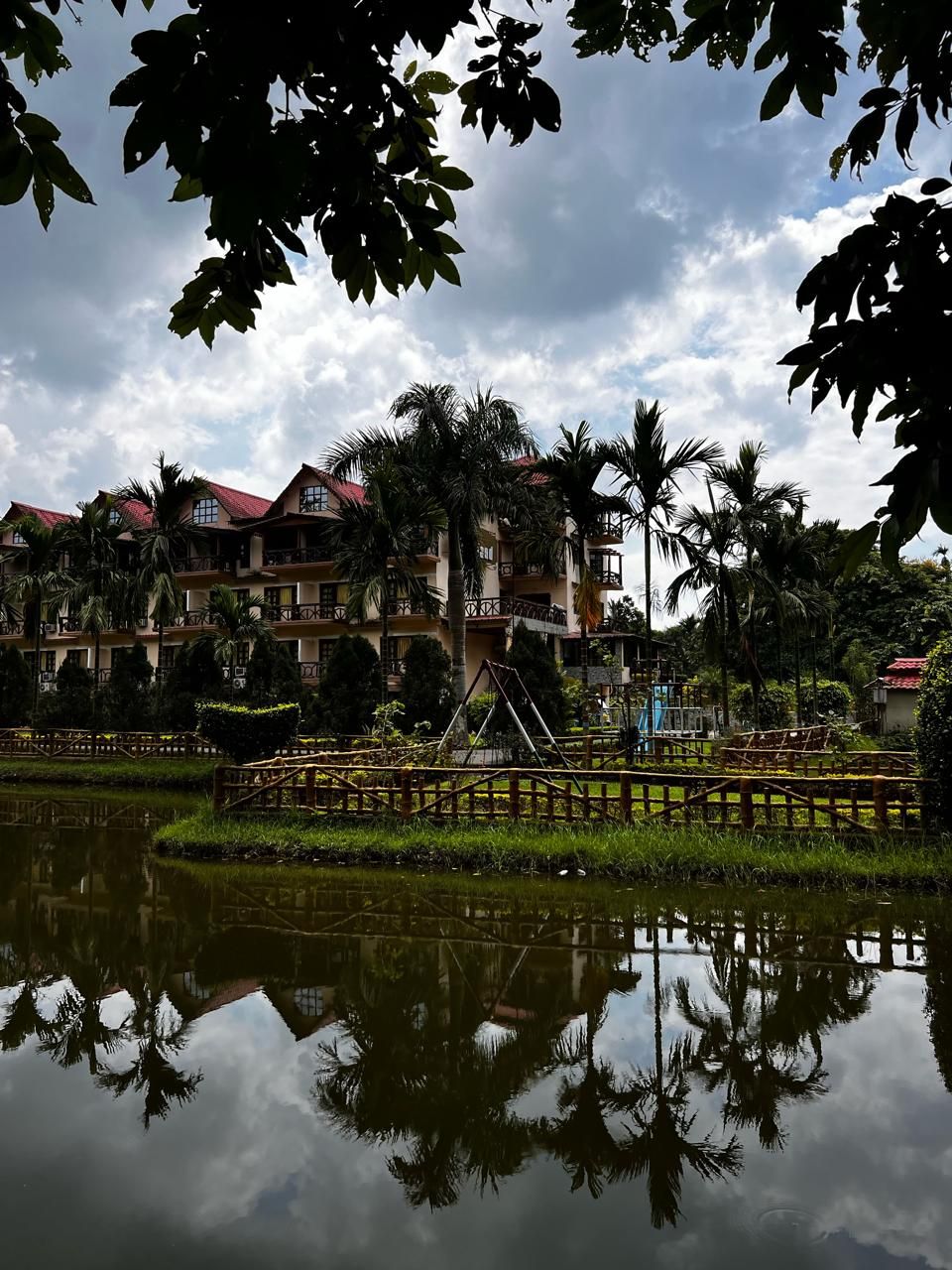 Un hotel con varios pisos, balcones y reflejo en el agua.