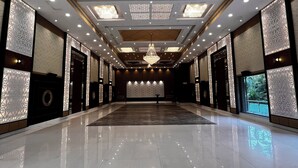 Un amplio y bien iluminado vestíbulo de hotel con piso de baldosas pulidas, diseño de techo hexagonal y paneles decorativos en las paredes.
