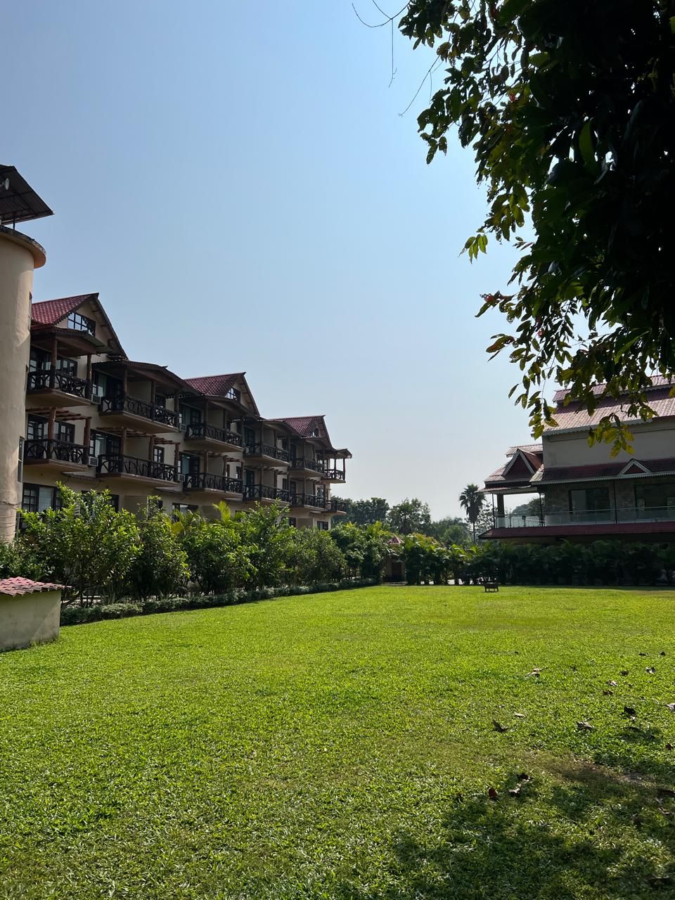 A hotel with multiple balconies, a well-maintained lawn, and a clear sky.