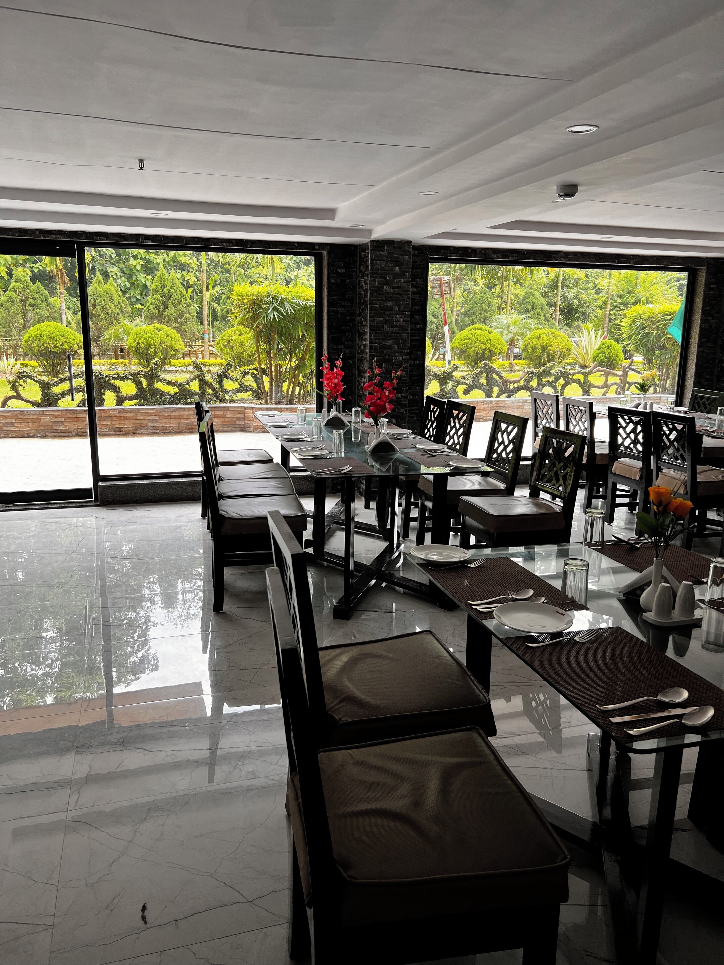 Un restaurant au décor moderne, doté de grandes fenêtres et offrant une vue sur la verdure environnante.
