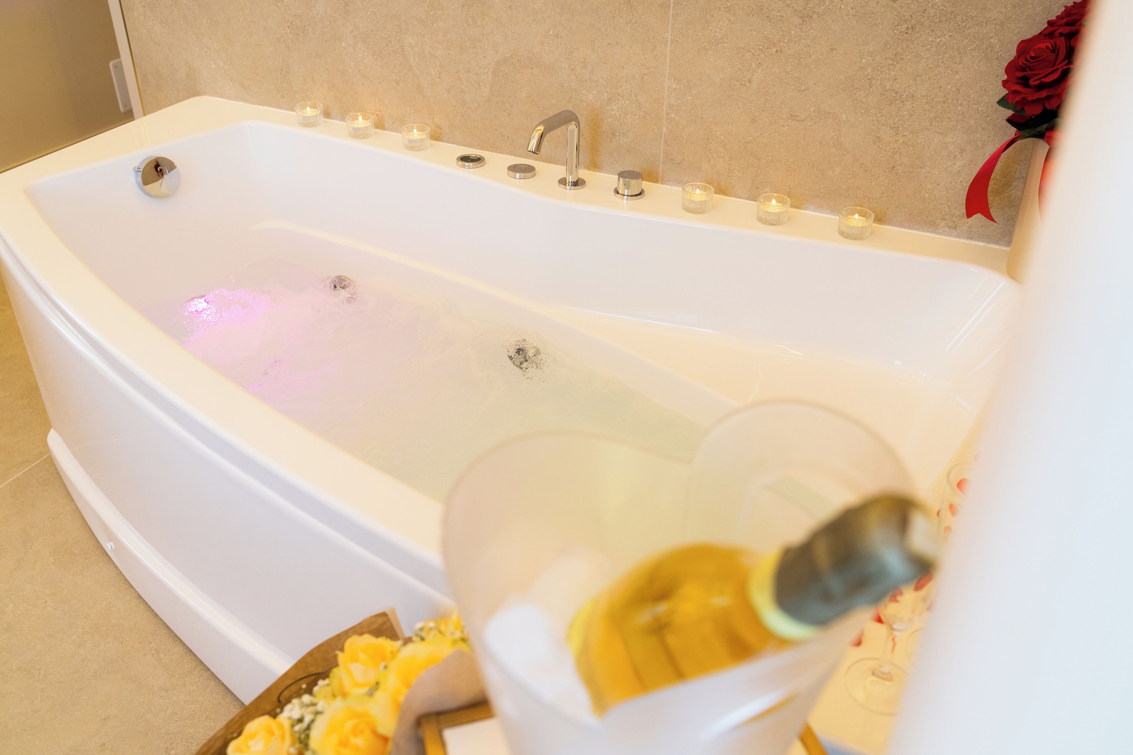 A bathtub with multiple faucets and candles.